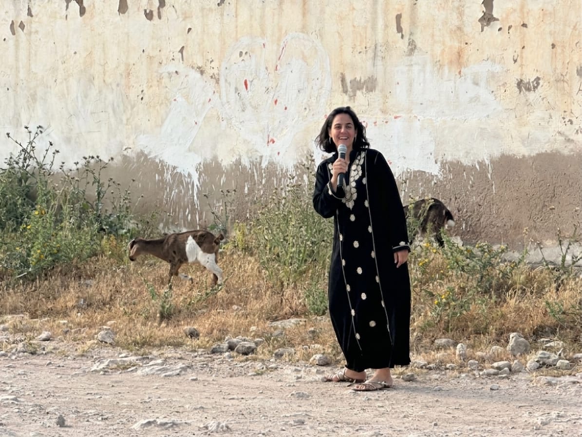 Fatima, micro en main, devant un mur d'Essaouira